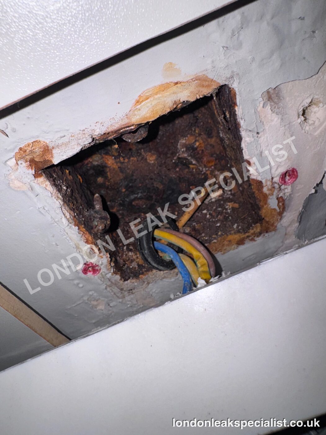 Corroded back box of a wet electrical socket opened up in a kitchen wall, from a job in N11, north London